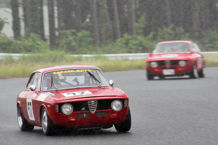 ハイパークリスタル／スーパークリスタル混走で雨に煙るコースを行く、2リッターエンジンを積んだ2台の「アルファ・ロメオ1300GTジュニア」。終始激しいトップ争いを展開した。