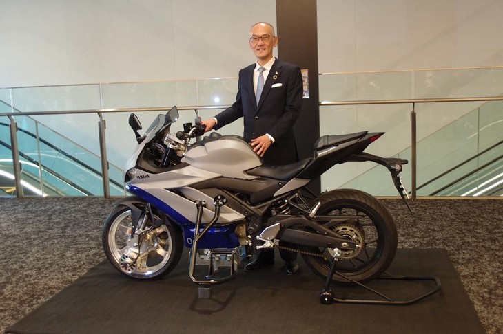 ヤマハ発動機の日高祥博 代表取締役社長と、「転ばないバイク」を実現するシステム「AMSAS」の実験車両。