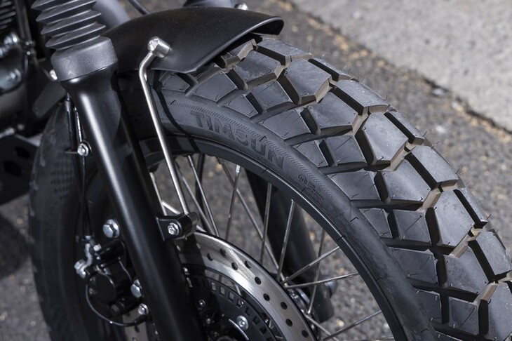 「ベニーズリミテッド」のベースとなるのは、ワイルドな趣が魅力の「GT-SR 250」。フロントフォークにはじゃばら状のブーツが備わり、前：120/90-18、後ろ：130/80-18サイズのワイドなセミブロックタイヤを履く。