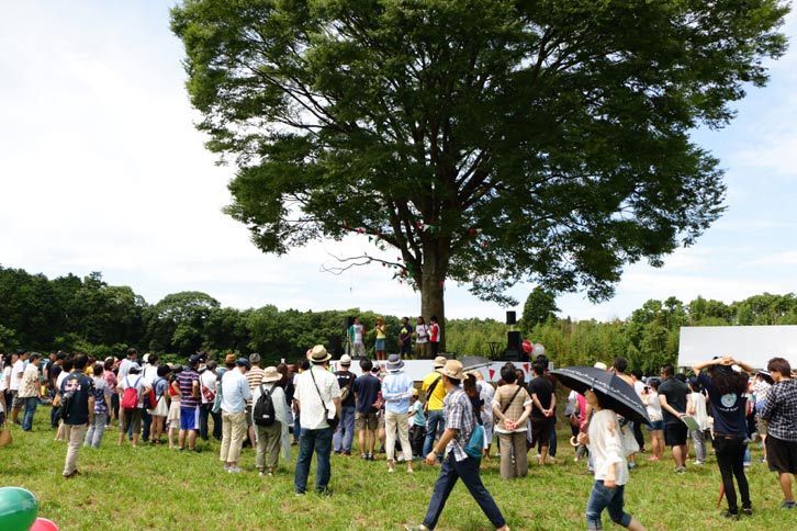 オートキャンプ場のシンボルツリーの下に設置されたメインステージ。会場へのアクセスは、都心から70分ほどと好立地にある。
			 