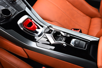 センターコンソールのスイッチ類。左に見える赤い部分がエンジン始動スイッチで、写真中央はリバースおよびトランスミッションモード選択ボタン。一番右が電動パーキングブレーキスイッチ。
    