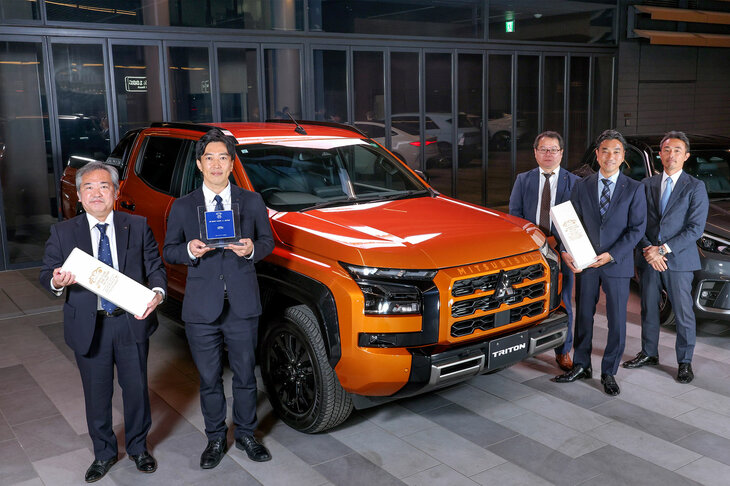 「2024-2025 COTY」で「デザイン・カー・オブ・ザ・イヤー」に輝いた「三菱トライトン」と、三菱自動車の関係者。　
	ほった「でも、“デザイン＝設計”ってことで、クルマの評価とカーデザインの評価が切り離せないとなったら、『日本カー・オブ・ザ・イヤー』とは別に『デザイン・カー・オブ・ザ・イヤー』なんて部門賞を設ける意味も、ないのでは？」　
	清水「そんな難しく考えちゃダメだよ。髪の毛が抜けちゃうよ」