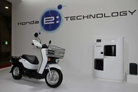 ワンタッチで交換できるバッテリーを2個搭載した「ベンリィe:」。右は街中に設置される充電スタンド。6個のバッテリーを収納・充電できる。