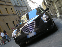 シエナ公文書館前にて。「SERVIZIO DI STATO」（公用）のバッジをウインドスクリーンに掲げてたたずむ2008年登録の「ランチア・テージス」。
    なお、今回紹介している写真の車両はすべて、オークション出品車両ではなく同型車。