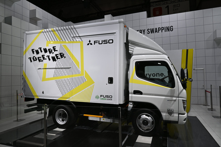 「三菱ふそうeキャンター」（バッテリー交換式モデル）と、バッテリー交換ステーション。