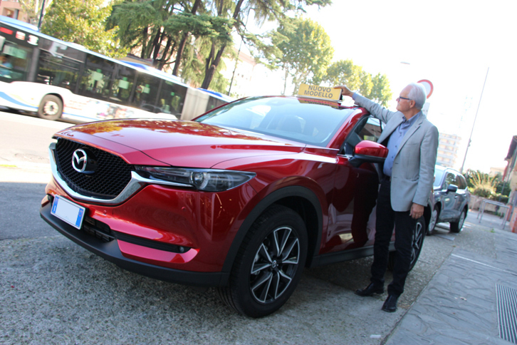 朝、「マツダCX-5」にNUOVO MODELLO（新型）のカードを掲げるエンツォ・ムニャイーニ氏。ムニャイーニ・アウトの社主である。