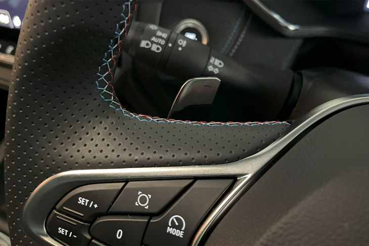 ブルー／ホワイト／レッドのトリコロールステッチで仕立てられた「キャプチャー エスプリ アルピーヌ マイルドハイブリッド」のステアリングホイール。マイルドハイブリッド車にはシフトパドルが備わる。