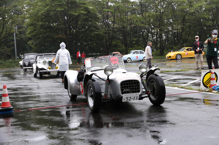 榛名湖畔の駐車場に特設されたPC競技のコースで、スタートする1952年「ロータスMk6」。今もケータハムなどで製造されている「セブン」のひとつ前のモデルで、女性ペアがドライブ。