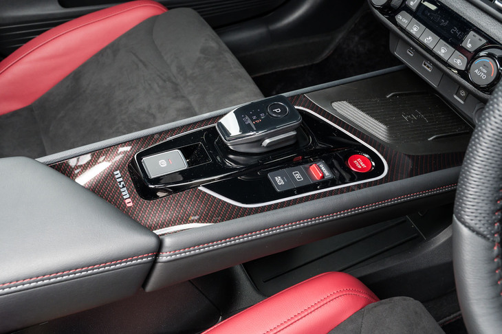 ブリッジ式のセンターコンソールには「NISMO」専用の赤いスタータースイッチとドライブモードセレクターが備わる。この写真では赤が織り込まれたカーボン調パネルがはっきりと確認できる。