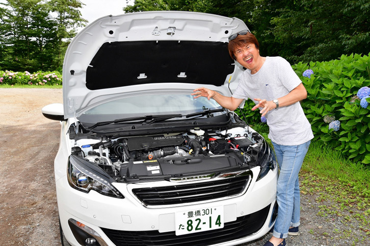 「プジョー308アリュール BlueHDi」のエンジンを前に、気合のヘン顔をキメる筆者。（写真＝池之平昌信）