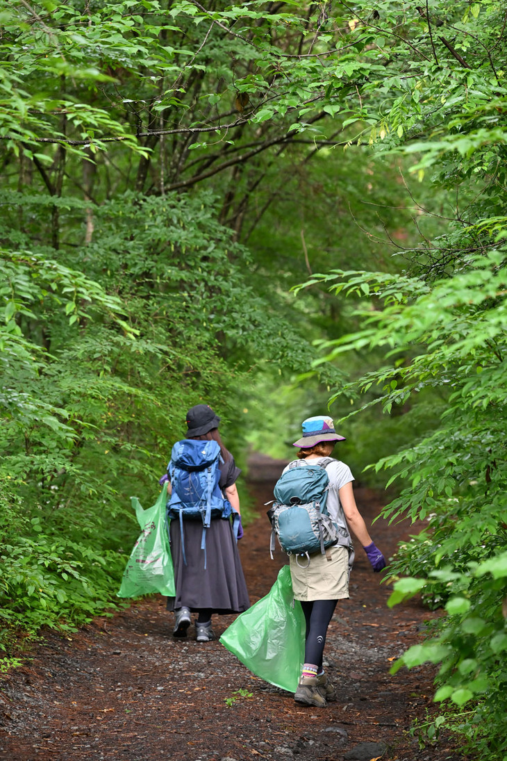 ゴミを拾うのはwebCG編集部のスタッフ3人（もう1人は撮影者＝筆者）。木々の緑が美しい。手に持っているのは富士吉田市指定の有料ゴミ袋。