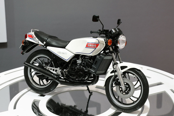 ハセガワはバイクでも注目の新製品を出してきた。1/12「ヤマハRZ250」。そろそろ2ストロークエンジン搭載車の終焉（しゅうえん）がささやかれはじめた1980年に突如としてデビュー、80年代の空前のバイクブーム、レーサーレプリカブームの火付け役となった伝説の2ストロードスポーツ。ちなみにアオシマのブースにも同スケールの同モデルのモックアップ（試作品）が展示されており、「ガチンコ対決か!?」と色めき立ったが、こちらはキットではなく塗装済み完成品としてリリース予定とのことだった。