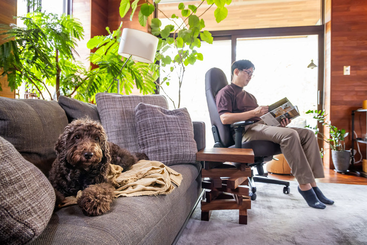 「アイコン ジャワエディション」をリビングに置き、愛犬とともにリラックスタイムを過ごす神戸アレック氏。座面と背もたれが連動して可動するシンクロロッキング機構で、ゆりかごのような自然で滑らかな動きが楽しめる。