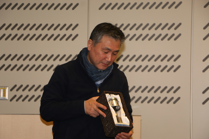 今年定年を迎えた、名車再生クラブの本間 健氏。プレゼントとして、かつてレストアした「日産スカイライン2000GT-R」に使用されていた、貴重なエンジン部品が手渡された。