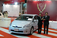 日本カー・オブ・ザ・イヤー実行委員長を務める三好正巳氏（右）から大賞のトロフィーを受け取る、プリウスのチーフエンジニア大塚明彦氏。