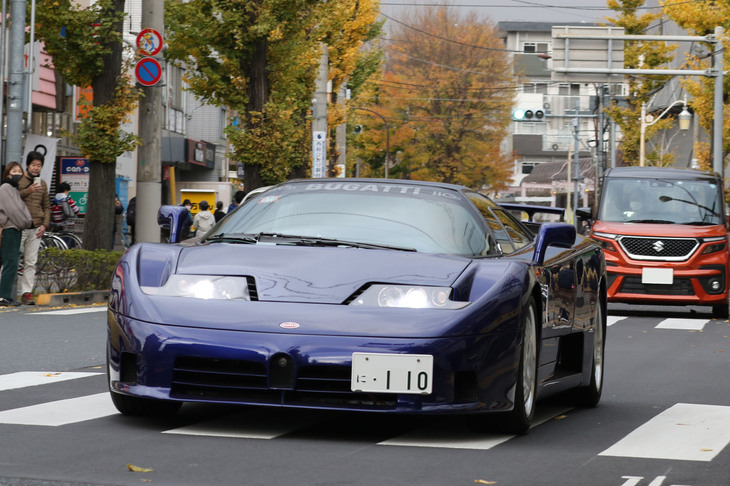 JR国立駅と谷保駅を結ぶ通称：大学通りを行く1992年「ブガッティEB110」。カーボンコンポジット製のシャシーに4基のターボを備え560PSを発生する3.5リッターV12 DOHCをミドシップした、デビュー時点ではド級のスーパーカー。