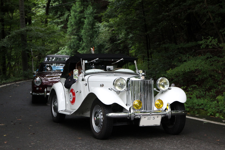 ゴール地点である浅間隠山（群馬県吾妻郡東吾妻町）にある「かやぶきの郷 薬師温泉 旅籠」に到着した参加車両。先頭は「品5」のシングルナンバー付きの1952年「MG TD」。