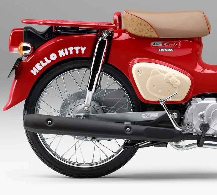 メーターやキーのデザインも専用の「スーパーカブ50ハローキティ」で、特に目を引くのが車体後半。フェンダーにロゴが添えられるほか、ハローキティのキャラクターを一部にプリントしたシートや、立体的にキャラクターをかたどったサイドカバーが装着されている。