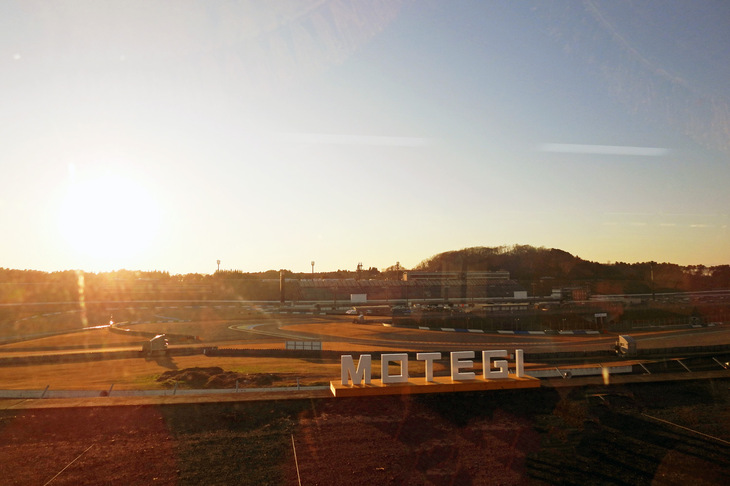 移動中のバスでは、「モビリティリゾートもてぎ」の隠れた名所も紹介。レースファンの間ではコースの下を通る狭いトンネルが有名で（レースカーを積んだトレーラーが、匠（たくみ）の技でくぐり抜けるのを見られるのだ）、構内路では際も標高の高いヘアピンの奥が最高のビュースポット。写真はオーバルコース コースサイドキャンプステイのフォトスポットだ。ご覧のとおり「夕日が素晴らしい！」とのことで新設された新名所で、「モビリティリゾートもてぎ」を訪れた折には、ぜひチェックしてみよう。