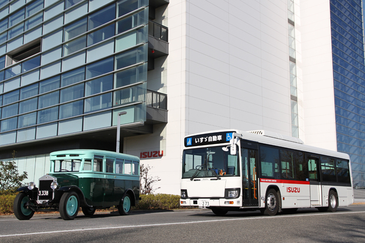 「スミダM型バス」と、藤沢工場内で構内バスとして使われている2016年「エルガ」。全長×全幅×全高＝11130×2485×3045mmのボディーに、最高出力250psを発生する5.2リッター直4のディーゼルターボエンジンを積んだ、最新の路線バスである。