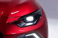 挑戦的な意匠のヘッドランプ。小さなレンズのまわりを黒いベゼルで縁取ったようなものとなっており、車体側には、人の目頭や目じりを思わせる凹面が施されている。