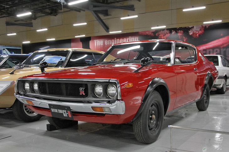 1973年「日産スカイライン ハードトップ2000GT-R」。初代「スカイライン2000GT-R」と同じ、直6 DOHC 24バルブ2リッターのS20型エンジンを搭載した、通称「ケンメリ」こと4代目スカイラインのGT-R（KPGC110）である。歴代スカイラインGT-Rのなかで唯一レースに参戦していないが、生産台数が200台未満と少ないことから、昔からヴィンテージ市場でプレミアム価格が付けられていた。中でもこの赤いボディーカラーは希少とのことで、昨今ではなんと9800万円の値札を掲げた個体も出現している。ちなみに新車価格は162万円だった。