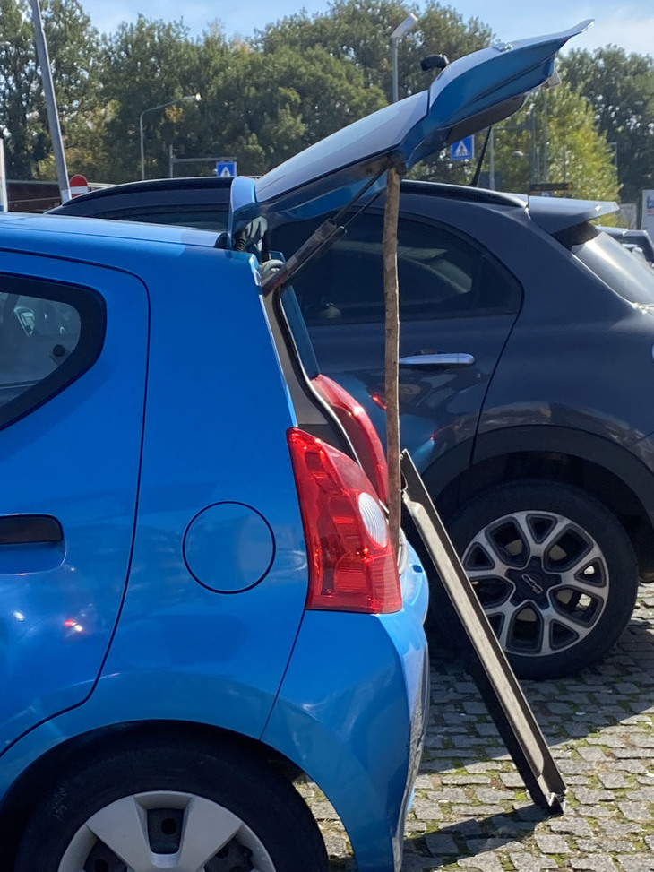 【写真E】棒でテールゲートを支える「スズキ・アルト」。向こうには荷室用トレーが立てかけられている。2021年秋に撮影。