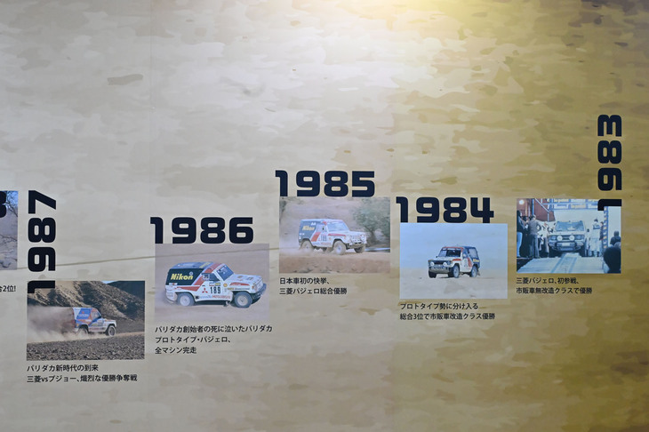 三菱のダカールラリーの戦歴をまとめたパネル展示（右から左へ時代が推移）。