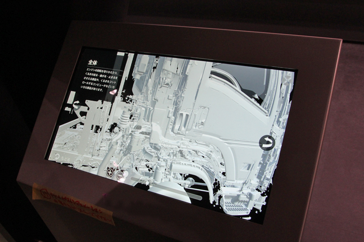 「いすゞのくるまづくり」および「いすゞの歴史」を紹介するコーナーでは、実物（実車）と模型に加えて、映像や画像も解説をサポートする。これは、タブレット大のディスプレイでトラックの構造を紹介するもの。画像を拡大するにしたがい、トラックがどんどん細かなパーツに分かれていく。そのイメージを、さまざまな角度から眺めることもできる。