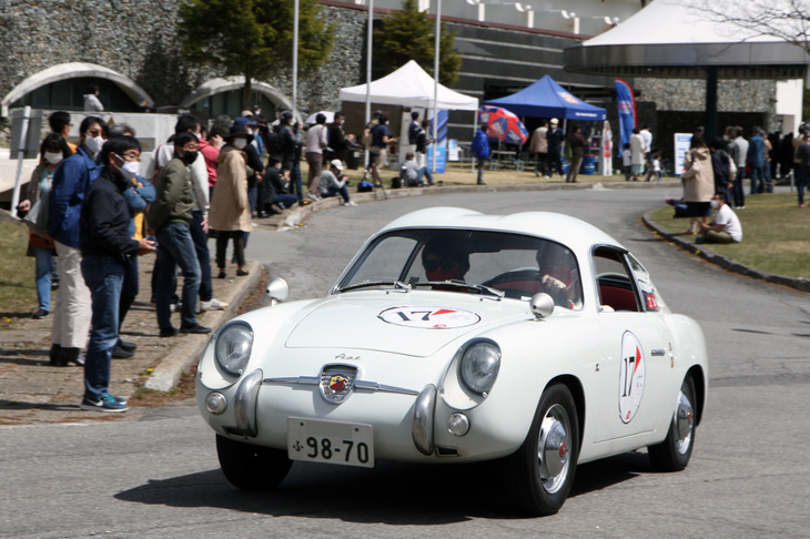 ギャラリーが連なる“花道”を抜けていく、ダブルバブルのルーフが特徴的な1957年「フィアット・アバルト750GTザガート」。