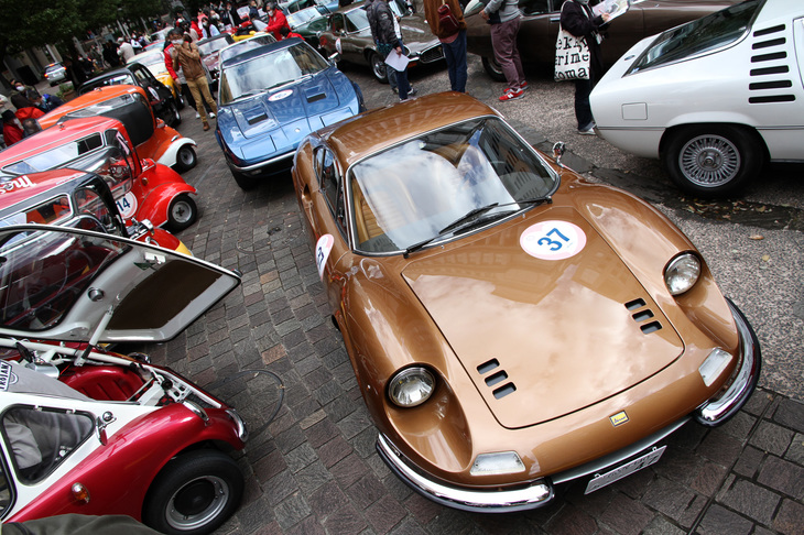 汐留西公園でスタートを待つ参加車両の一部。手前の珍しいブラウンメタリックの1970年「ディーノ246GT」の後ろは1971年「マセラティ・インディ」。左側に並ぶのは「BMWイセッタ」や「メッサーシュミットKR200」などのバブルカー群。