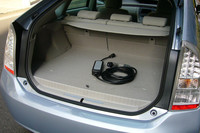 荷室の床下には、ノーマルのニッケル水素バッテリーに比べ、体積で3倍、容量で4倍勝るリチウムイオンバッテリーがおさまる。結果、ラゲッジスペースを1割侵食。フロアボード下のエクストラスペースも失われた。（写真中央のコード類は、充電用の専用アダプター）