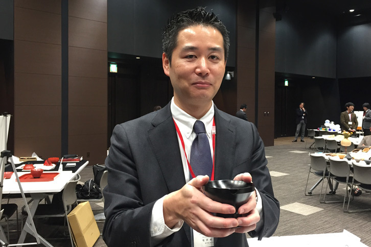 出展した「角杯」を手にする浄法寺漆産業の松沢卓生さん。代表取締役として商品のプロデュースを数多く手がける。