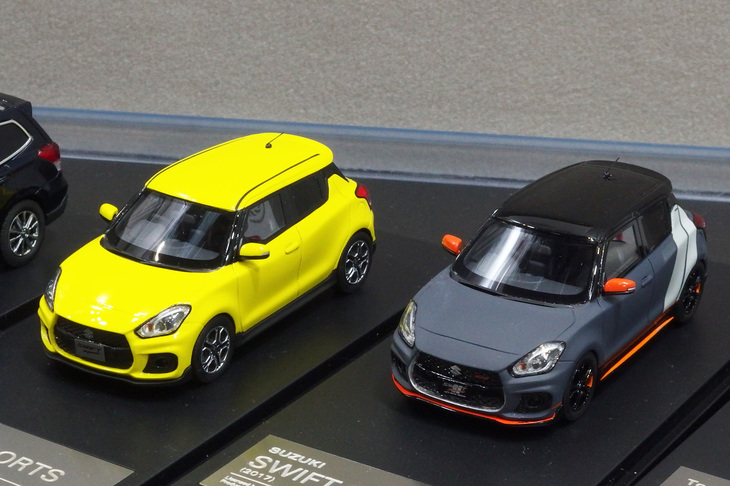 ハイ・ストーリーの「スズキ・スイフトスポーツ」。右側は2018年の東京オートサロンのスズキブースに出展された仕様。発売時期未定で価格はノーマルが9504円、オートサロン仕様が9936円。