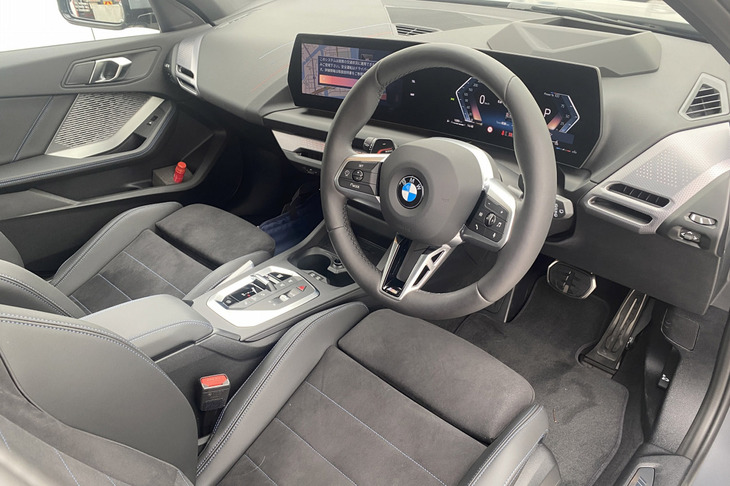 BMWではおなじみとなったカーブドディスプレイを採用する「1シリーズ」のコックピット。センターのシフトパネルには、小さなレバー式のシフトセレクターやドライブモードセレクター、スタート／ストップスイッチなどが並ぶ。