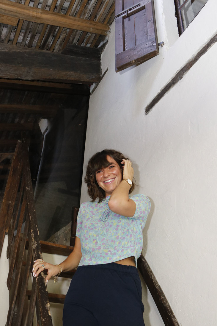 屋根裏部屋に続くはしごと、案内してくれたスタッフのカロリーナ・トスカーニさん。