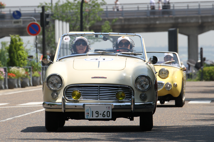 1960年「ダットサン・フェアレディ」（SPL212）。フェアレディの名を最初に冠した北米輸出専用車。その名にふさわしい女性ペアがドライブ。