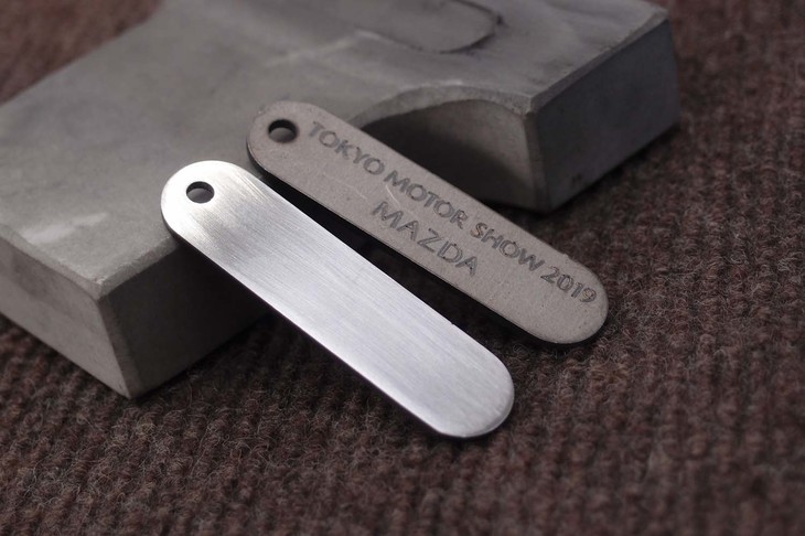 マツダのテーマは、ボディーパネルの成型に使う金型磨き。その代わりとして、小さな金属プレート（ただし、本物のクルマの部材）を研磨する。写真右に見える粗い地肌が、作業後は左のようにピカピカになる。