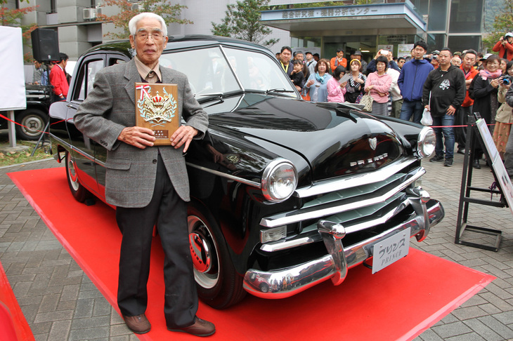 ラリーの上位入賞者らが受賞した表彰式で、特別賞を授与された花井 覚さん。新車から乗り続けて車齡50年を迎えた1968年「ダットサン・サニークーペ」で毎年参加している花井さんは、今年でめでたく満100歳！ さすがにご自分では運転されてなかったが、すこぶるお元気でそのお年には見えない。副賞として「『プリンス・セダン』の運転席に座る権利」も与えられた。