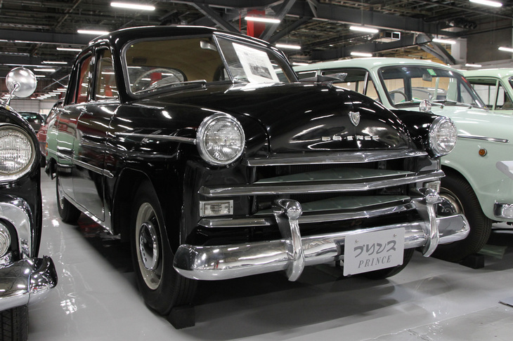 1954年「プリンス・セダン」（AISH-2）。国産小型車（5ナンバー）で初めてOHVを採用した1.5リッター直4エンジンを積んで、1952年に登場した、当時の国産最高級車である。そもそもプリンスというブランドは今上天皇の、皇太子時代の立太子の礼にちなんで命名されたもので、皇室と縁の深いメーカーだった。中でもこの個体は、今上天皇が皇太子時代に実際に愛用していたという特別な一台。