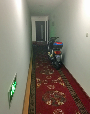 アパートの高層階で。廊下には、住人のものと思われるスクーターが。