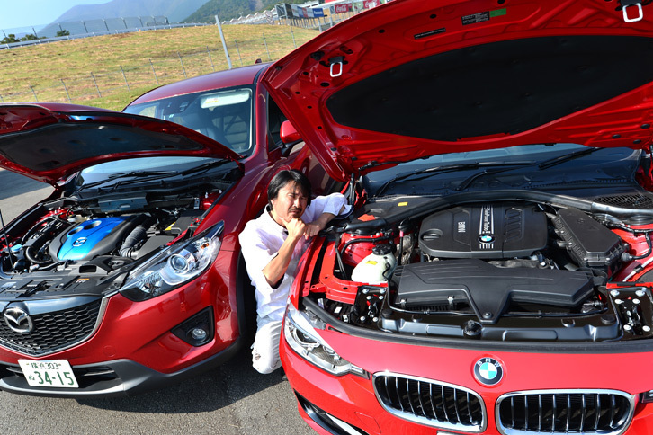 「BMW 320d」と「マツダCX-5 XD」のエンジンルームを比較中の筆者。（写真＝池之平昌信）