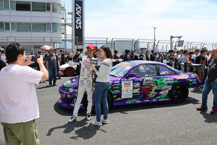 「D1GPエキシビションマッチ ラウンドゼロ」出場選手との交流も「スーパーグリッドウォーク」の楽しみのひとつ。ファンとの記念撮影に応じる、Mind Control Racing SHIBATIREの横井昌志選手。