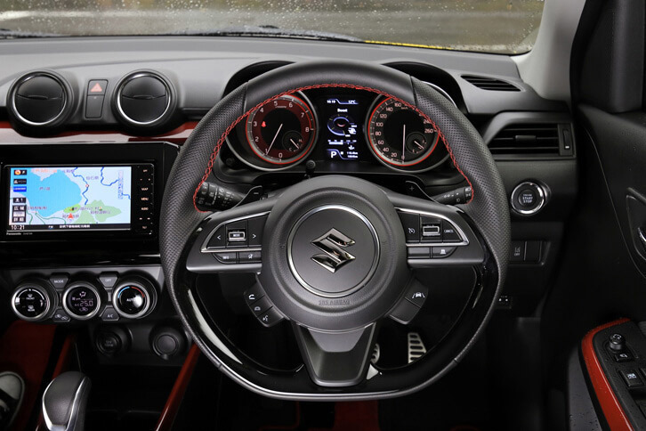 赤いステッチが目を引くフラットボトムタイプのステアリングホイール。手がすべるのを防ぐため、グリップ部の皮革にはディンプル加工が施されている。