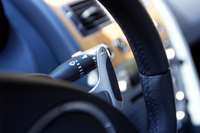 革のストリップが貼られたDB9のパドル。このパドルを操作したとたん、6ATはマニュアルモードに移り、「AUTO」には、センターコンソールのボタンを押し直さないと復帰しない。ノーマルのMTモードでは、レブリミット直前に自動的にシフトアップするが、フロアコンソールにある「Sport」ボタンを押すと、あくまで現状のギアを維持する。「Sport」モードか否かは、右後ろ斜め下を見て、「Sport」ボタンのランプ点灯を確認しないとわからない。少々不便。メーターナセル内でモードが表示されるようになるといいのだが……。