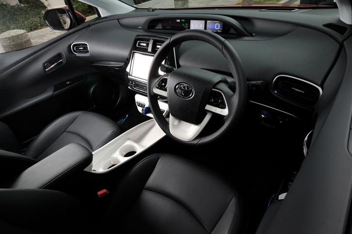 新型「プリウス」のインストゥルメントパネルまわり。先代モデルの特徴だった、ダッシュボードとアームレストをつなぐような意匠のセンターコンソールは廃止され、代わりに2つのドリンクホルダーを持つコンソールトレーが採用された。