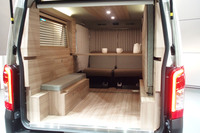 車内カーテンやウッドブラインド、AC100V電源、スポット照明付き木目調ルーフパネルなどが備わる「キャラバンMYROOMローンチエディション」の室内。