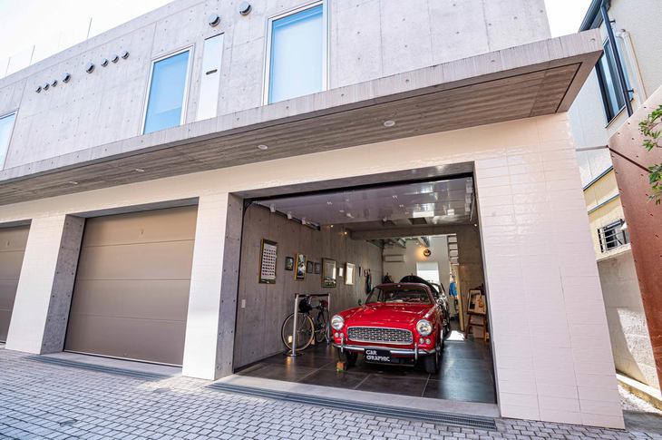 モダンなガレージハウスの外観。1階がタイル仕上げ、2階部分はコンクリートの打ちっぱなし。シャッターは電動式だ。