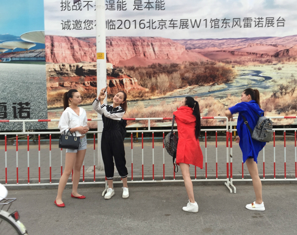 コンパニオンとおぼしき女性たちが、ゲートの外で自撮りを楽しむ。