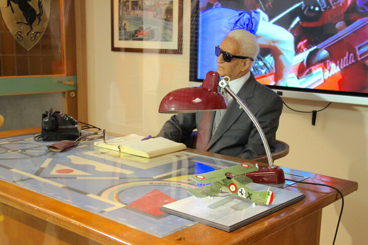 イタリア・マラネッロの「ムゼオ・フェラーリ」で。エンツォ・フェラーリのろう人形も置かれた執務室の再現。天板に置かれたガラスの下に、ピレリ社の抽象絵画風ポスターが透けて見える。